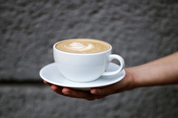 young man holding a cup of coffee on concrete background