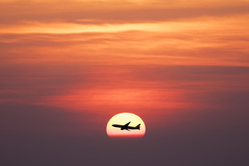 Beautiful sunset with silhoette air plane is flying through the sun.