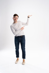 Full length portrait of a cheerful young man wearing casual clothes isolated over white background, pointing away at copy space.