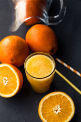 Fresh orange juice and fresh fruit oranges on a black background