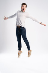 Full-length photo of funny man 30s in casual t-shirt and jeans jumping isolated over white background.