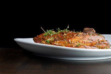Roast pork knuckle on white plate, sprinkled with rosemary.