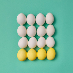Pattern in the form of a square of painted yellow and white eggs on a green background with copy space. Billiard game concept. Flat lay