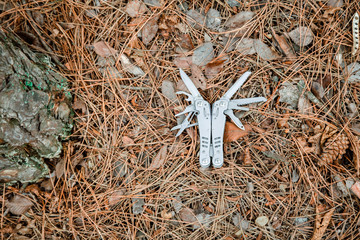 multi tool knife on the ground covered with pine needles