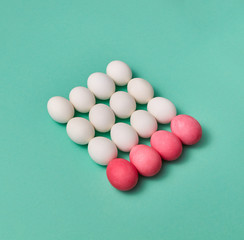Set of white and pink colored eggs in the form of a square on a green background with copy space for text. Billiard balls concept
