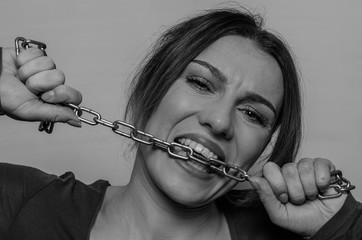 Young beautiful girl bites the chain with her teeth, trying to figure it out