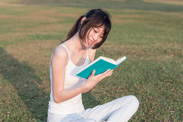 Obraz premium young woman reading a book in the park