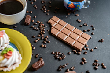 flat lay of chocolate bar with sweets and coffee beans on dark background