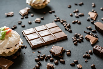 flat lay of chocolate bar with sweets and coffee beans on dark background