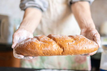 baker's hands cook bread top view and holding fresh cooked loaf.