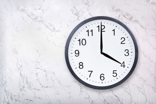 Wall clock show four o'clock on white marble texture. Office clock show 4pm or 4am on marble background