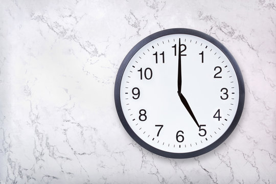 Wall clock show five o'clock on white marble texture. Office clock show 5pm or 5am on marble background