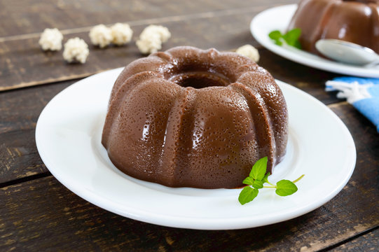 Tasty chocolate pudding on white plates on a dark wooden background. Light low-calorie dessert for breakfast.