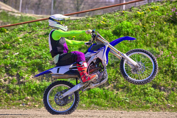Fototapeta premium biker on motorcycle stunts while driving on the rear wheel side view