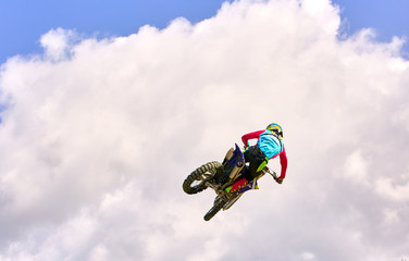 Fototapeta premium Motocross Rider Jump in a blue sky with clouds