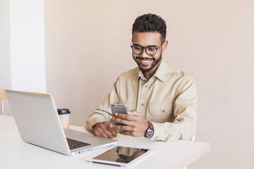 Young handsome man using smart phone and laptop at home. Businessman or student working on computer...