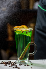 Winter green cocktail with orange and cinnamon in glass cups. Cinnamon and Rosemary Spices.