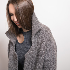 Beautiful young girl in gray coat posing in studio.