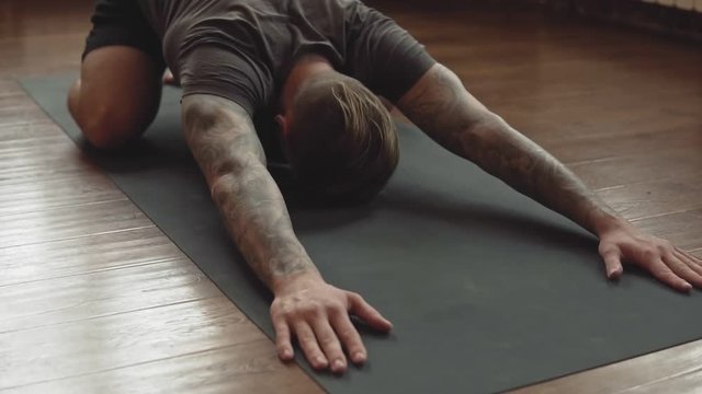 Close-up of Young man doing yoga in studio with wooden floor. Freedom, health and yoga concept.