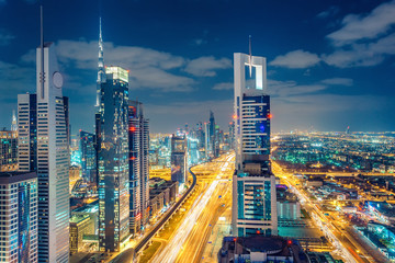 Fototapeta na wymiar Colourful nighttime skyline of a big modern city. Dubai, United Arab Emirates. Aerial view on highways and skyscrapers.