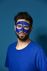 Portrait of handsome man with paint on his face against color background