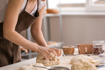 Obraz na płótnie Canvas Female baker making dough in kitchen