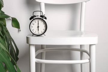 Alarm clock on chair against white background