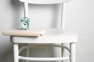 Alarm clock and book chair against white background