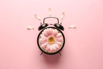 Alarm clock with flower on color background