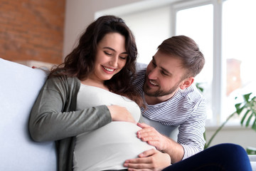 Happy pregnant couple resting at home