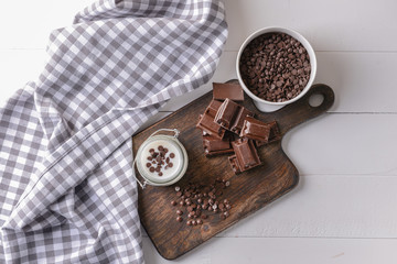 Jar with tasty yogurt and chocolate chips on white table