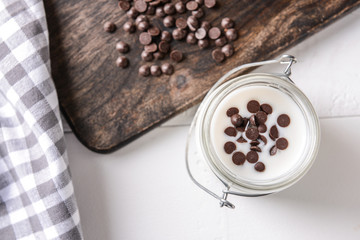 Jar with tasty yogurt and chocolate chips on white table