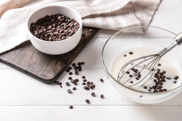 Preparing of tasty dessert with chocolate chips on white table