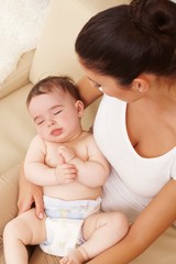 Cute naked baby sleeping in mother's arms