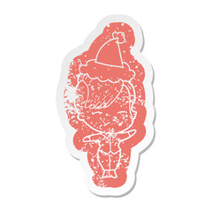 cartoon distressed sticker of a squinting girl wearing santa hat