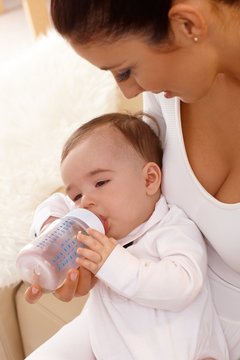 Mother feeding baby from feeding bottle