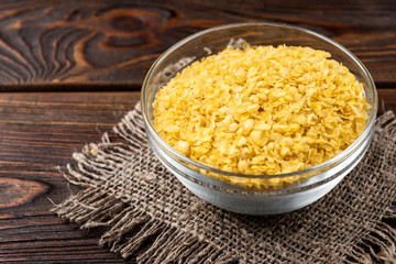 Millet flakes on dark wooden background.