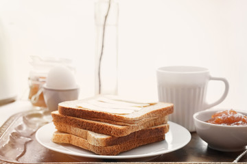 Tasty toasts, boiled egg, cup of coffee and jam on metal tray