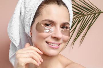 Woman with under-eye patches on color background