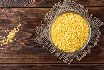 Millet flakes on dark wooden background.