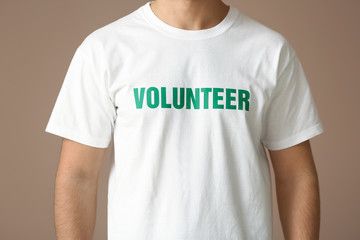 Young male volunteer on color background