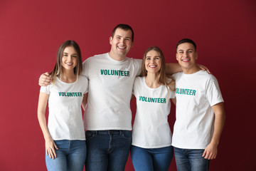 Team of young volunteers on color background