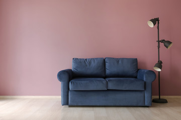 Comfortable sofa and lamp near color wall
