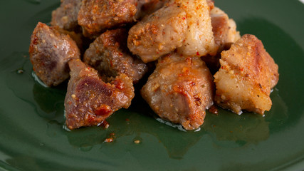 Hot pork slices. Delicious baked crispy pork slices and crispy skin beautiful color close up on green background. junk food