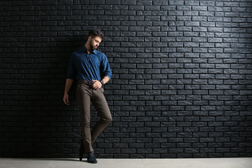 Fashionable young man against dark brick wall
