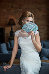 A bride closes face by dollars fan in loft interior room