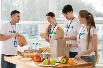 Young volunteers with food for poor people indoors