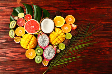 Assortment of exotic fruits with tropical leaves on wooden background