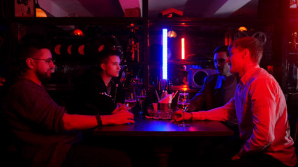 Bar with neon lighting. Group of friends sitting by the table