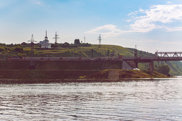 Fototapeta premium a Volga shore in the light of late sun with a train going to the bridge
